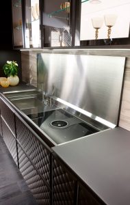 Cucina BELGIO, dettaglio del sistema CONCHIGLIA, piano in acciaio rivestito con vetro retroversiciato, uguale al top, con movimento di apertura automatico, sotto il quale cono posizionati lavello e fuochi con cappa aspirante integrata.
